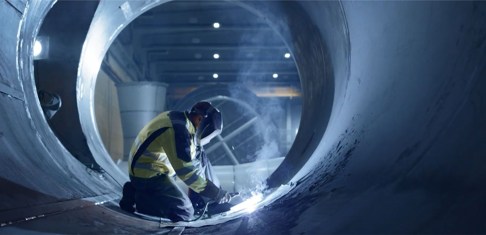 person welding in a large tube